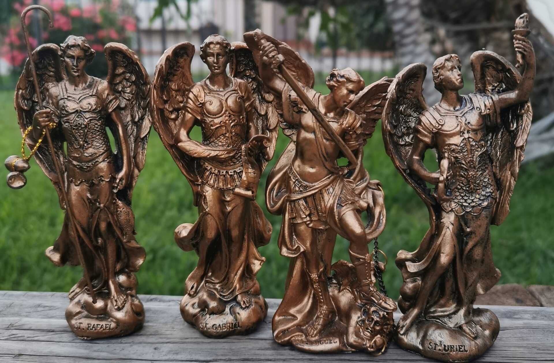Four bronze statues of angels are sitting on a wooden table