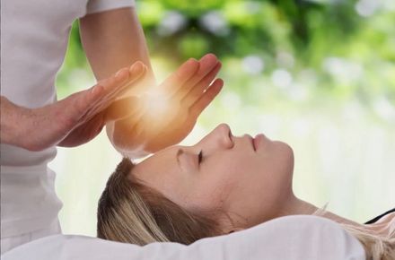 A woman is getting a healing session from a person.