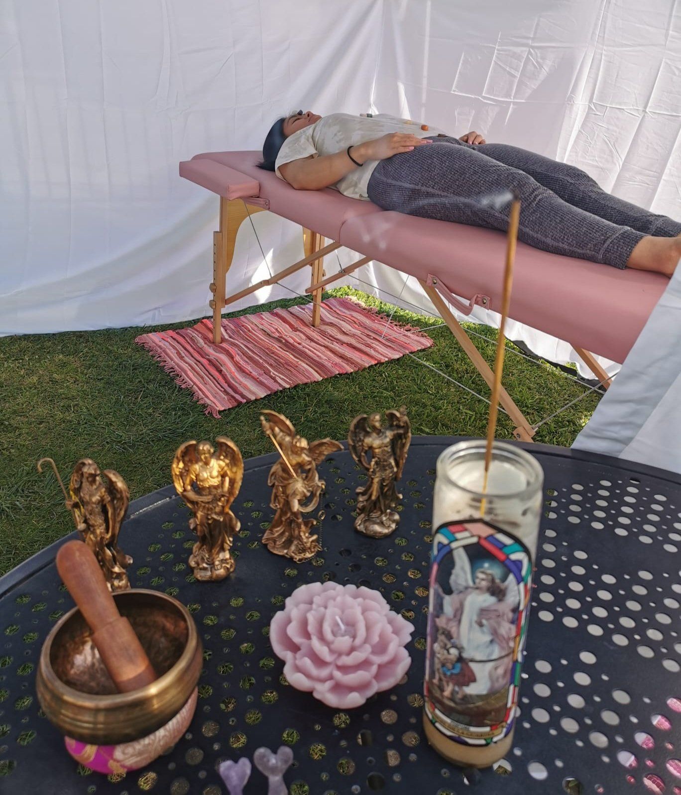 A woman is laying on a table with candles and angels