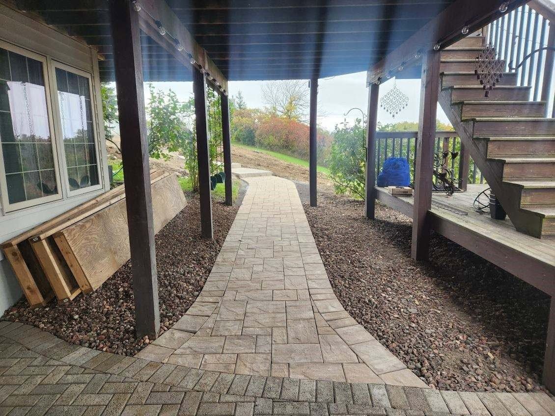 Covered stone walkway beside a house, with stairs on the right and a garden path leading outdoors.
