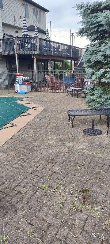 Courtyard with brick paving, patio furniture, a pool on the left, and a balcony on a building above