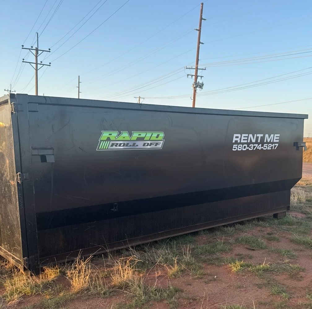 A large dumpster is parked in front of a building under construction.