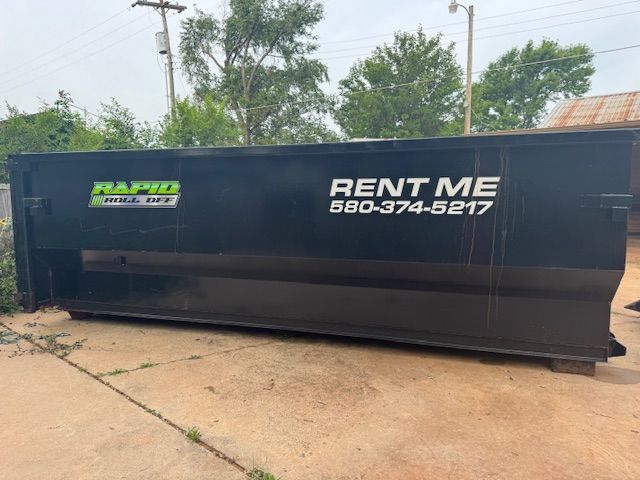 A green dumpster is sitting on the side of the road