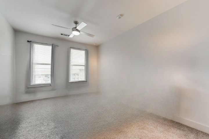 Before staged - Empty room with carpet, two windows, and a ceiling fan.