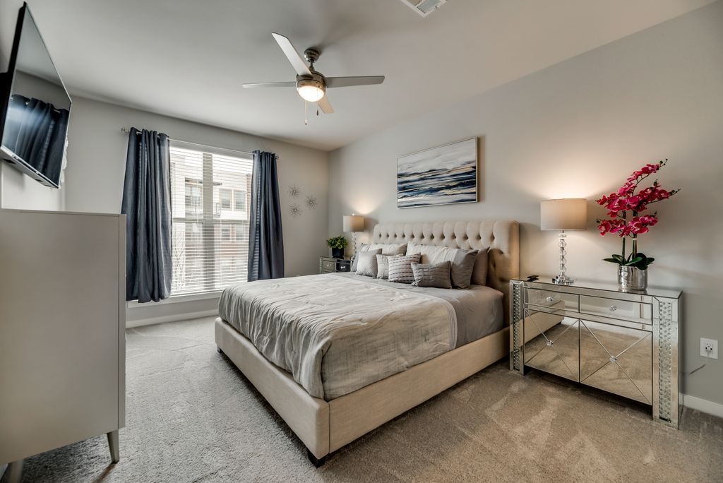 Move-in-ready furnished bedroom with a made bed, lamps, artwork, and storage