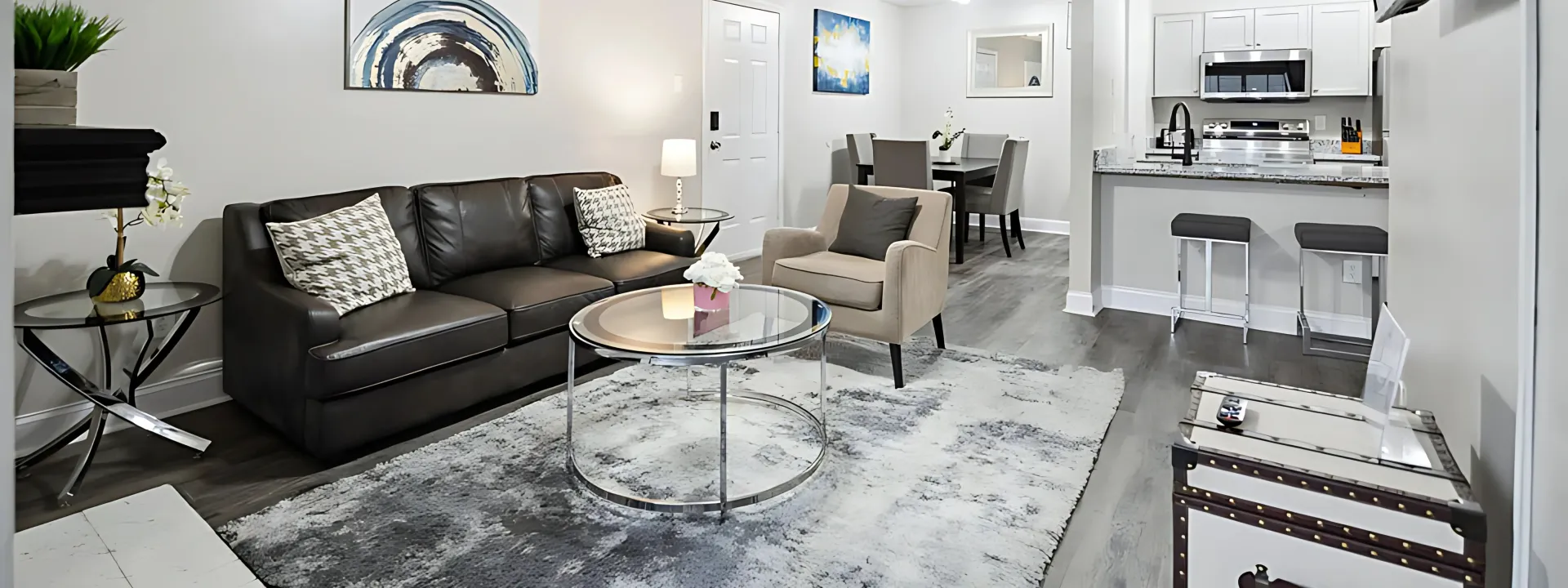 Living room with dark leather sofa, gray rug, and open kitchen.