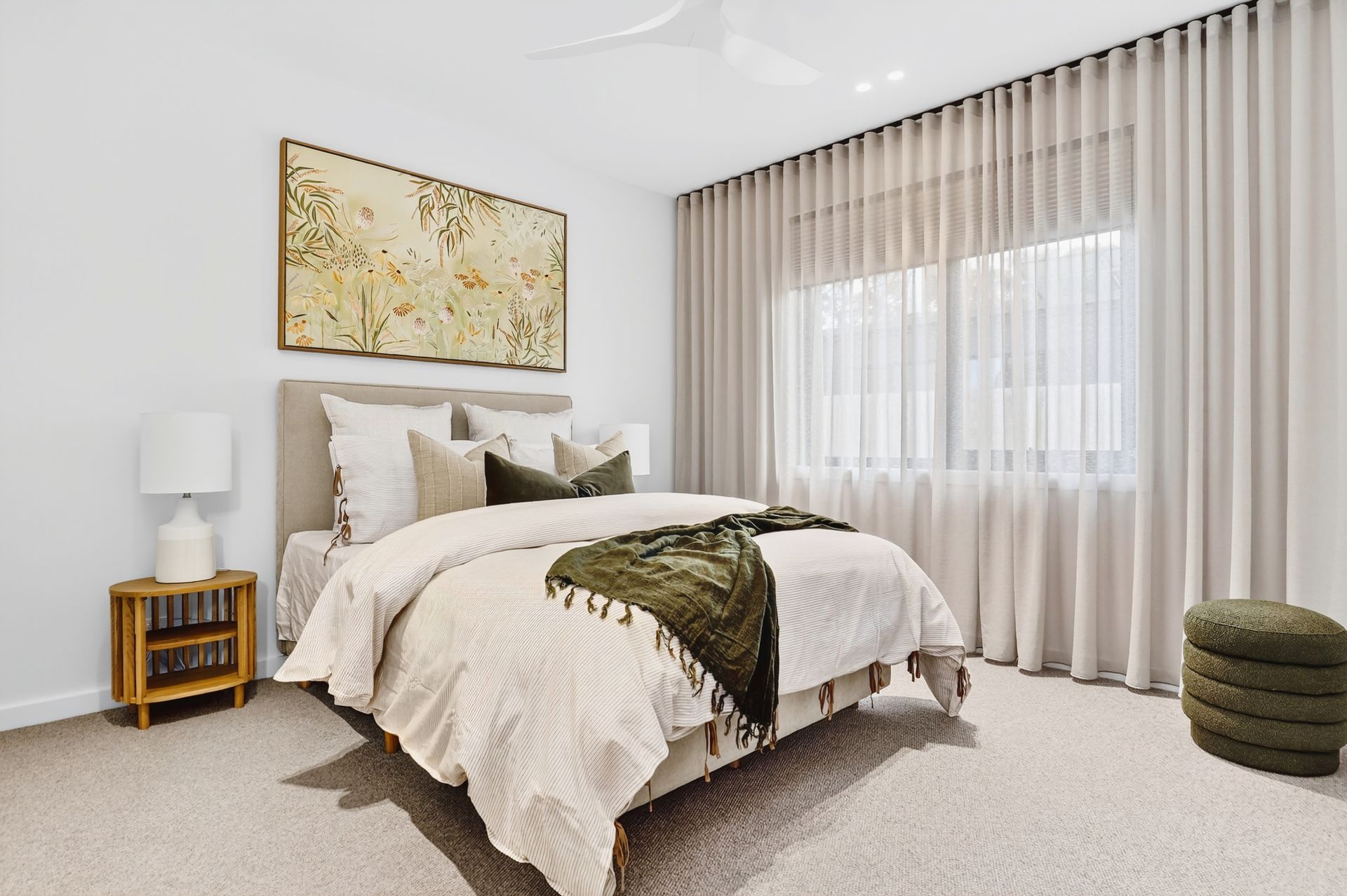 Bedroom with neutral tones, a large bed, artwork, and flowing curtains.