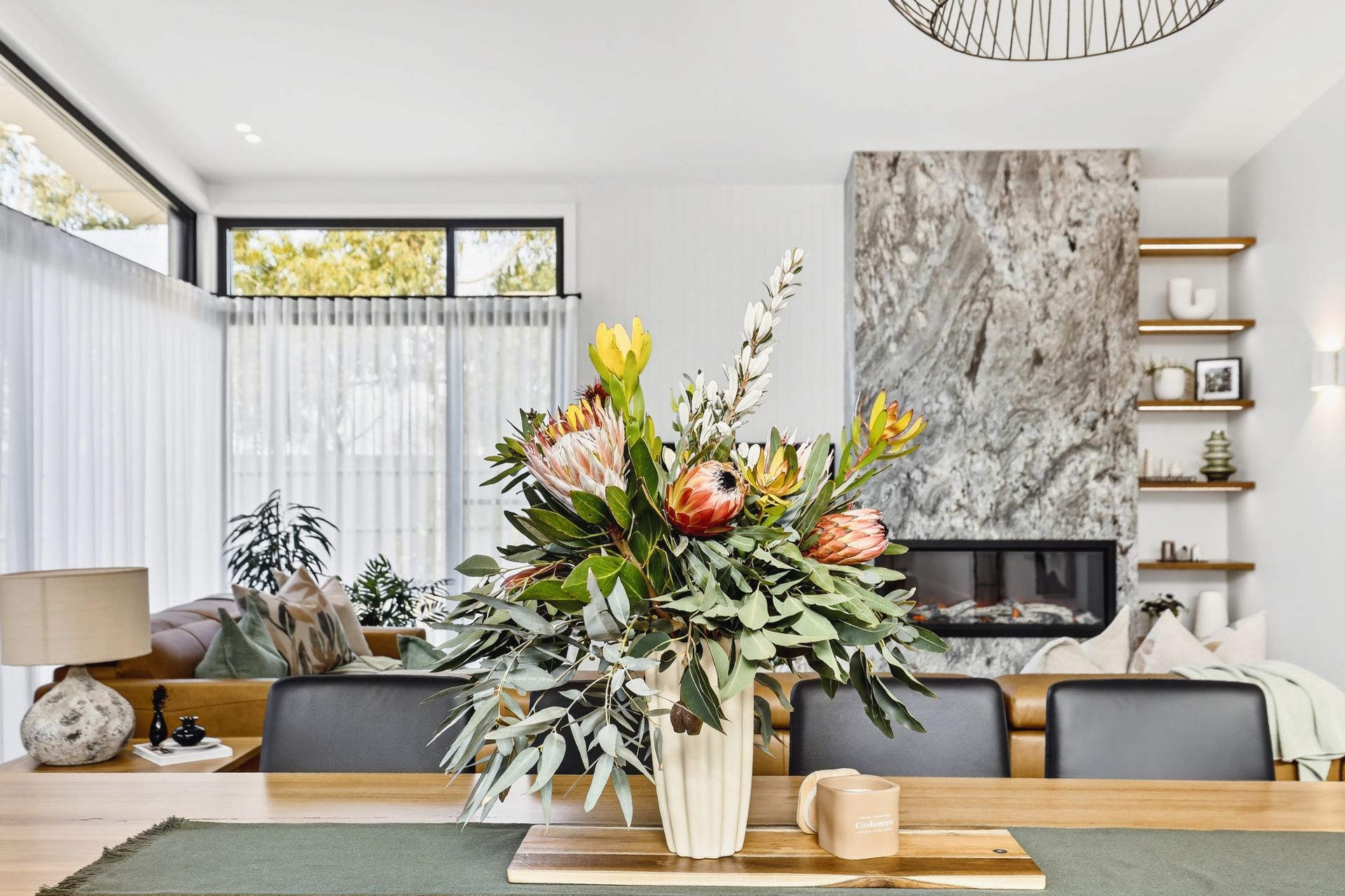 Dining room with large floral arrangement, fireplace, and modern decor.