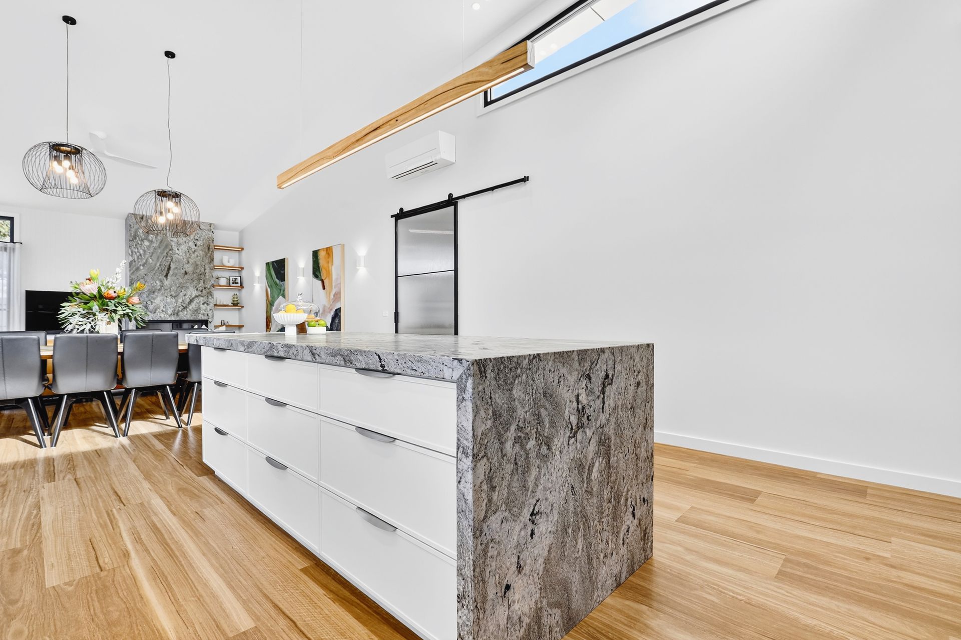 Modern kitchen with white cabinets, granite island, and hardwood floors.