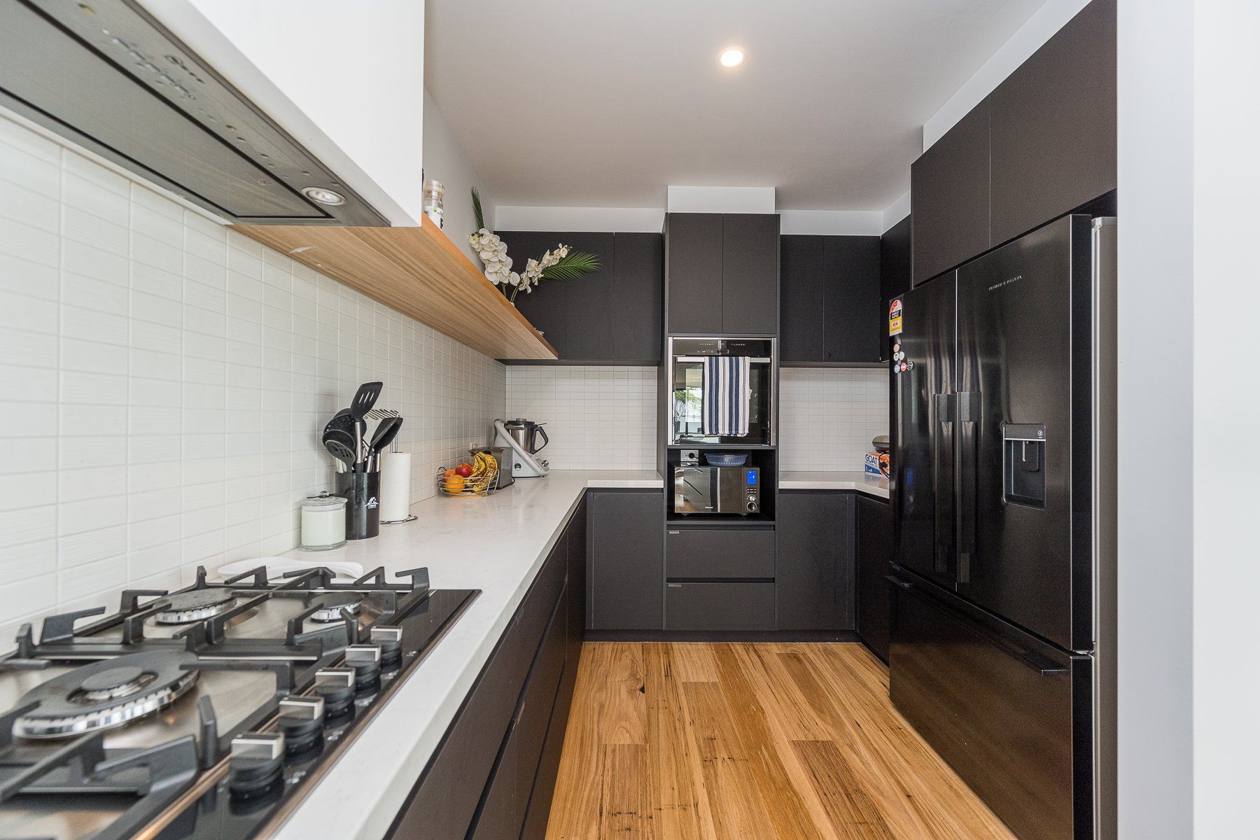 A kitchen with a stove top oven , refrigerator and microwave.
