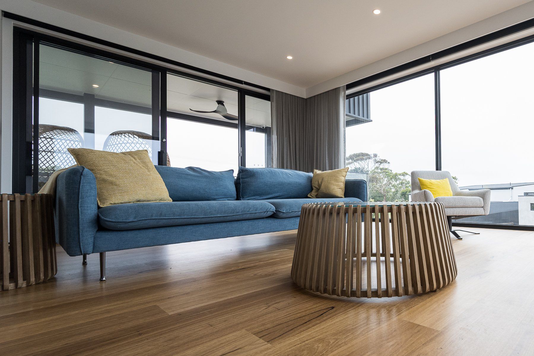 A living room with a blue couch and a wooden table.