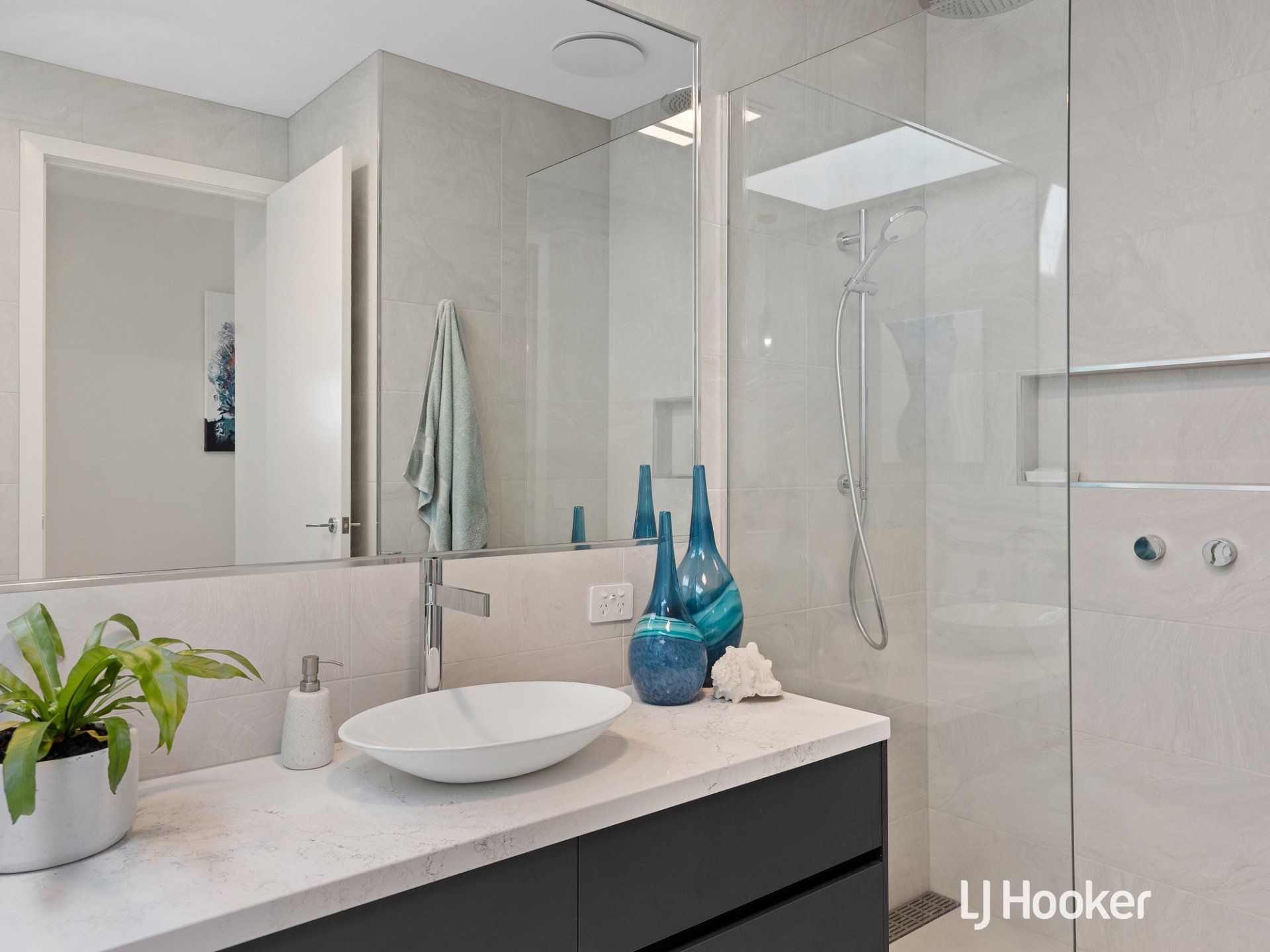 A bathroom with a sink , mirror , and walk in shower.