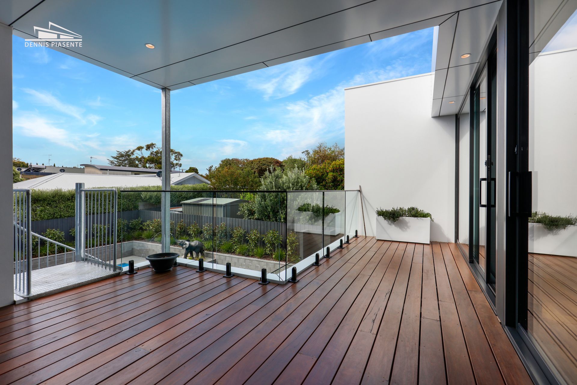 A large wooden deck with a glass railing in a house.