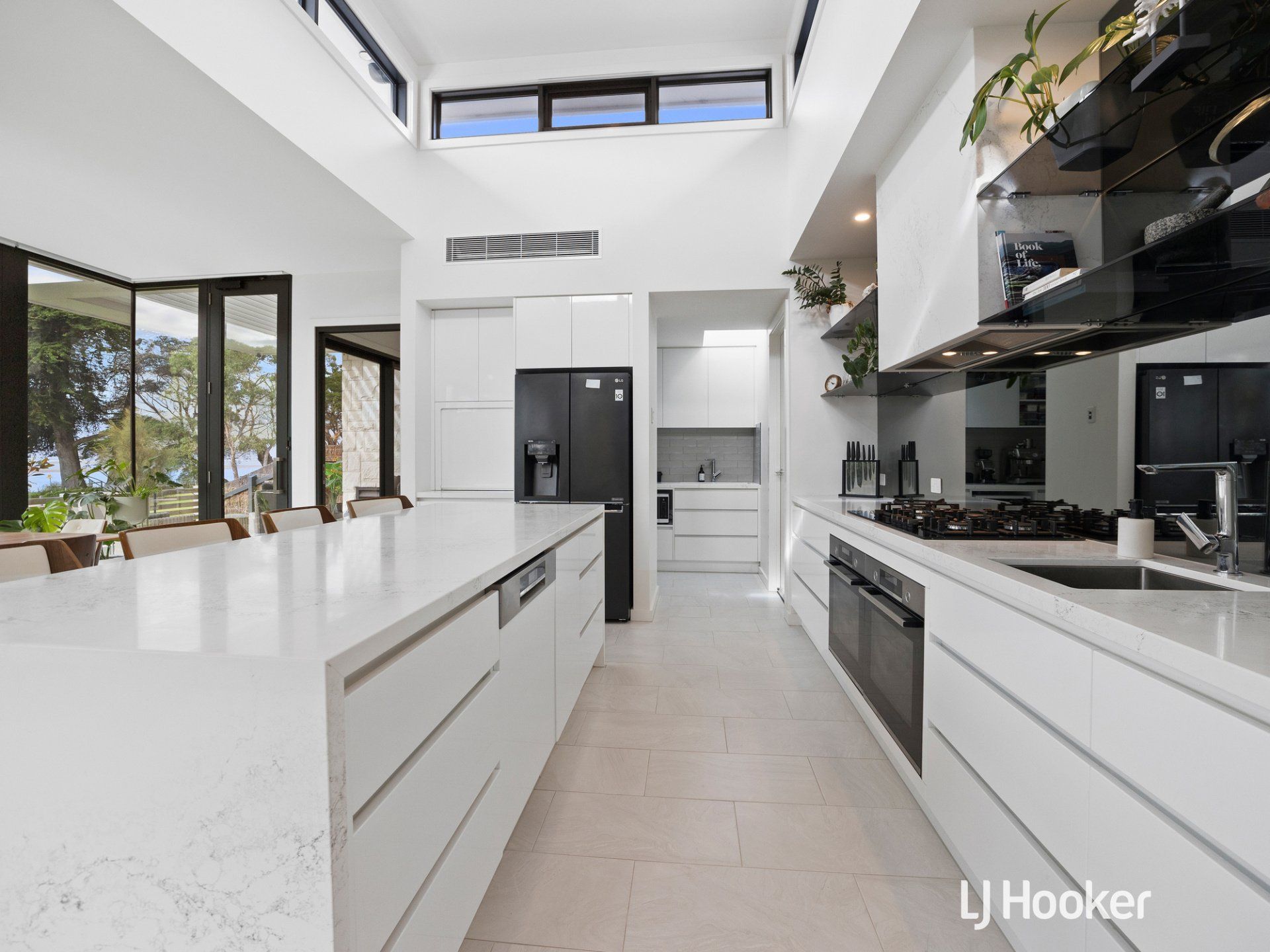 A long kitchen with white cabinets and black appliances