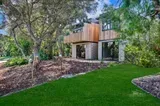 A house with a lot of windows is surrounded by trees and grass.