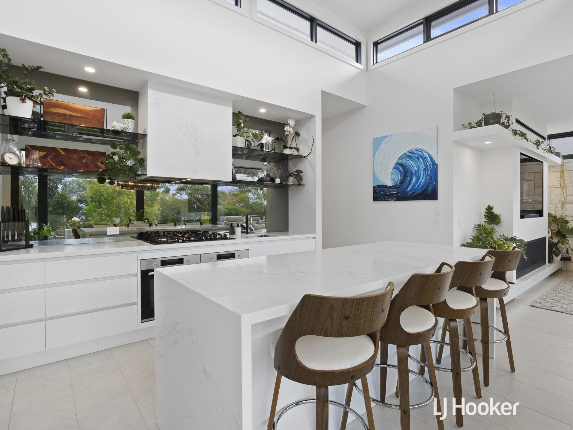 A kitchen with a large island and stools and a painting on the wall.