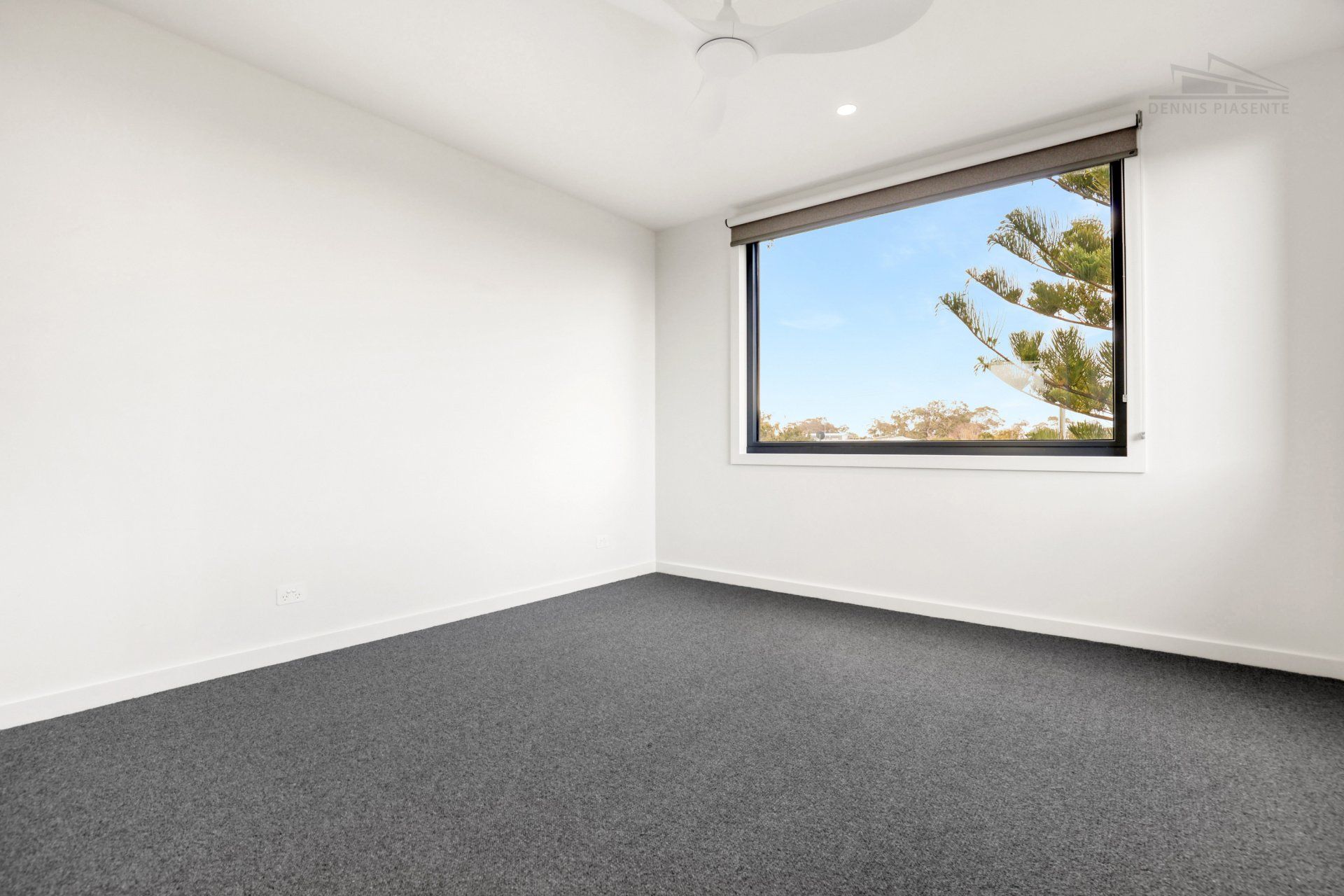 An empty bedroom with a large window and a ceiling fan.