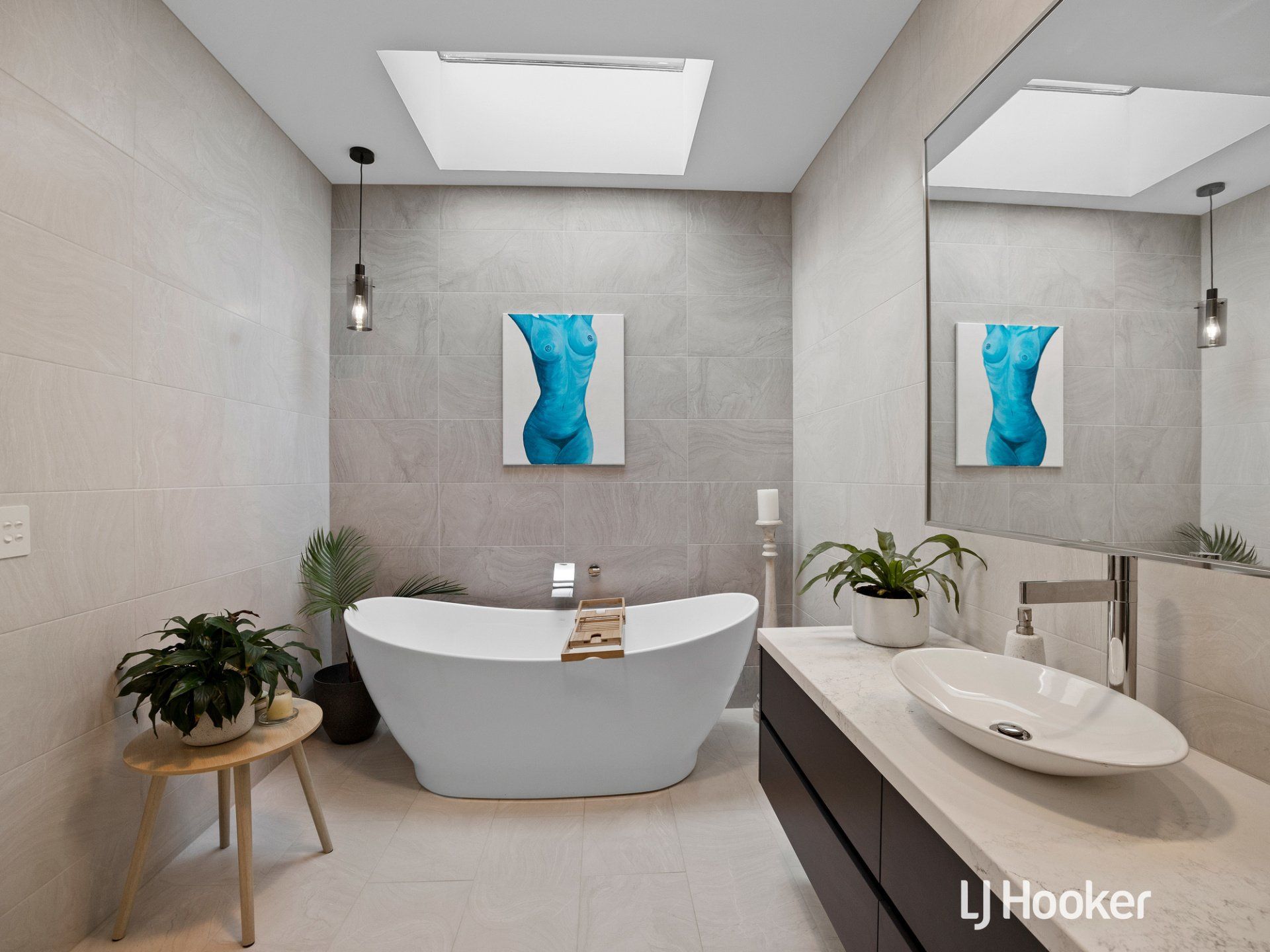 A bathroom with a bathtub a sink and two paintings on the wall