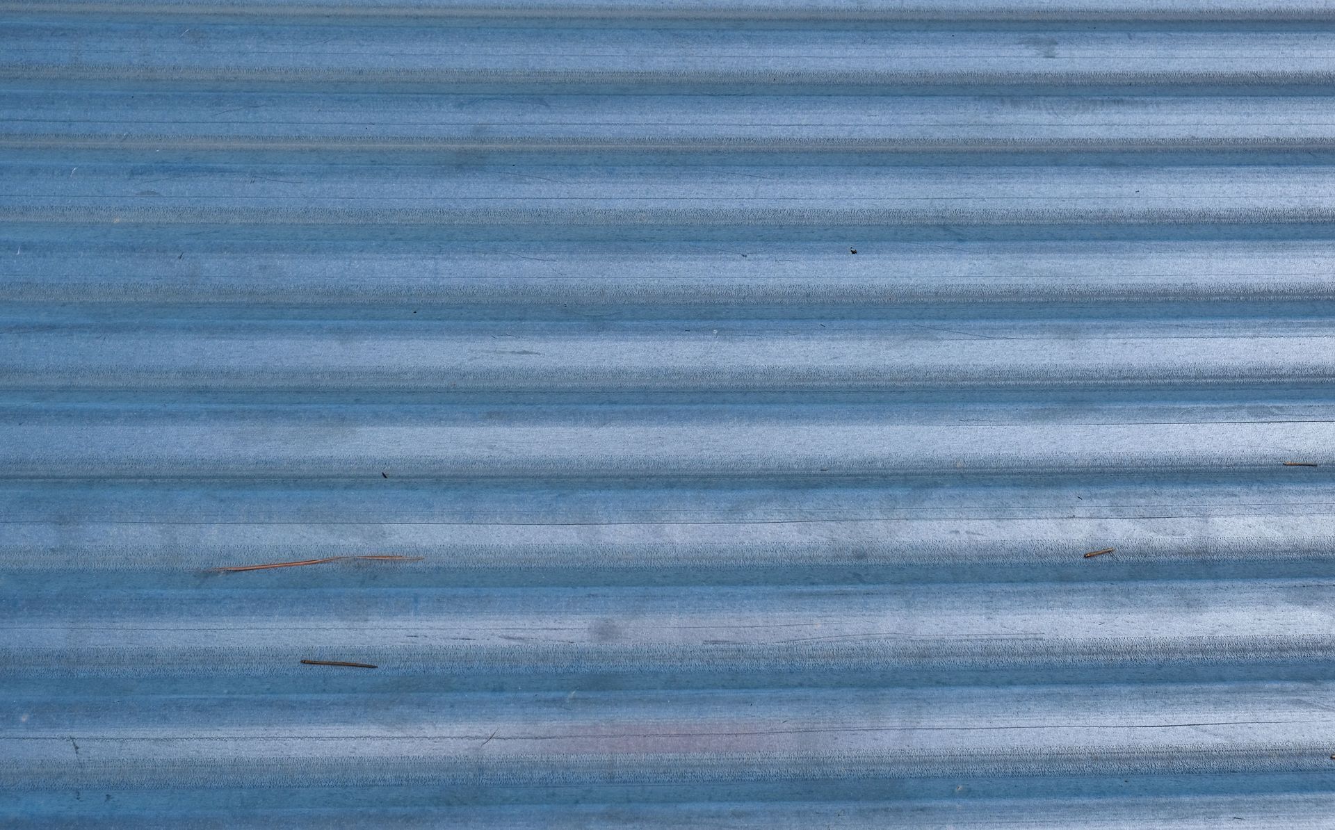 Blue corrugated metal wall with horizontal ridges and a few small rust spots
