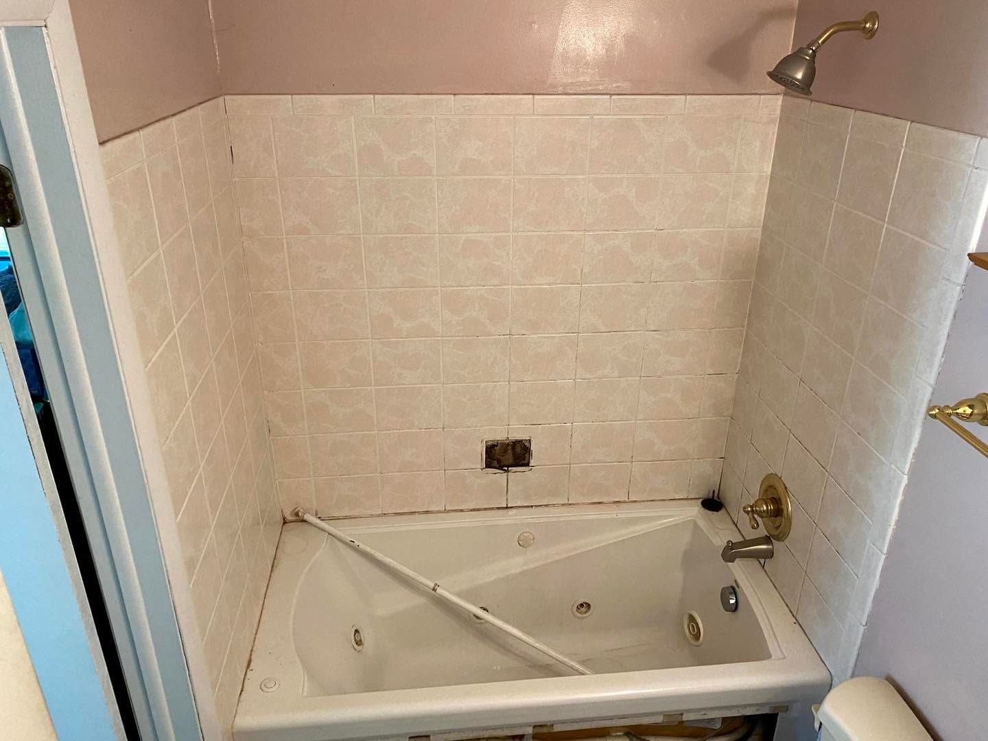 Small beige tiled bathroom with a corner bathtub and shower fixture