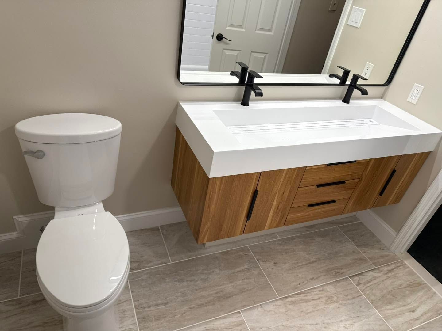 Bathroom with white toilet and wood vanity with double sinks and mirrors