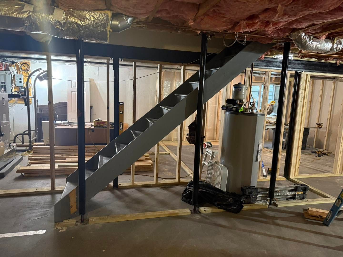Basement with unfinished walls and a black metal staircase rising to the upper floor.