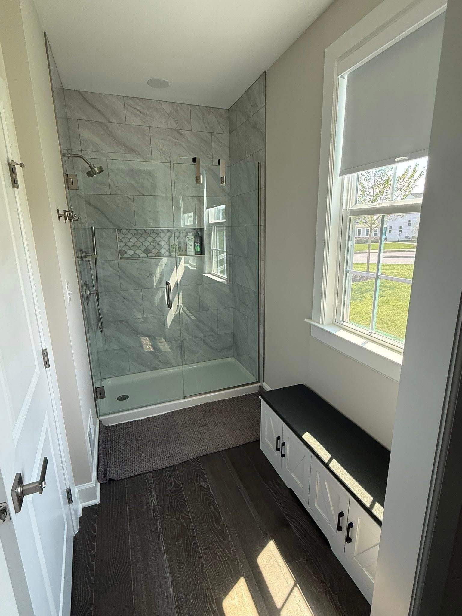 Small modern bathroom with marble shower, window, and built-in bench seat