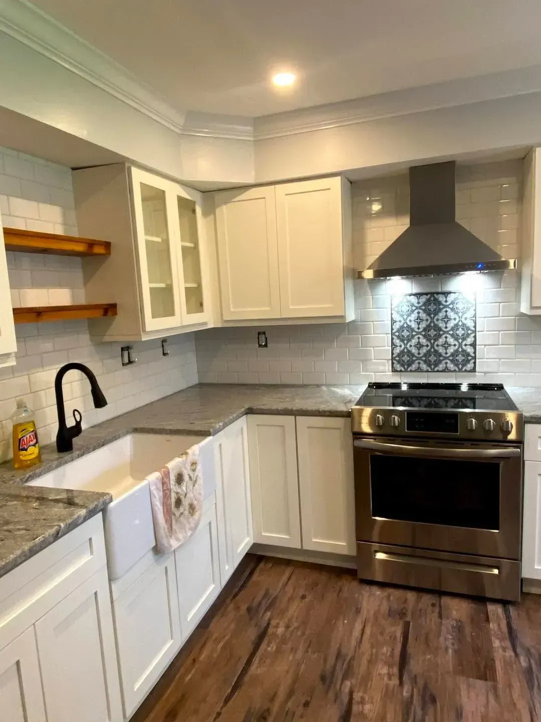 Bright kitchen under renovation with white cabinets, island, tools, and a yellow step ladder