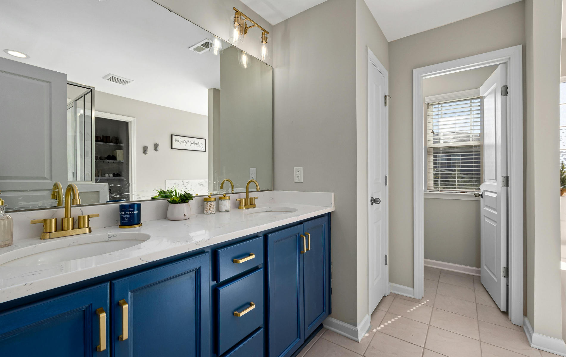 Modern bathroom vanity with blue cabinets, white countertop, and doorway to a tiled shower area