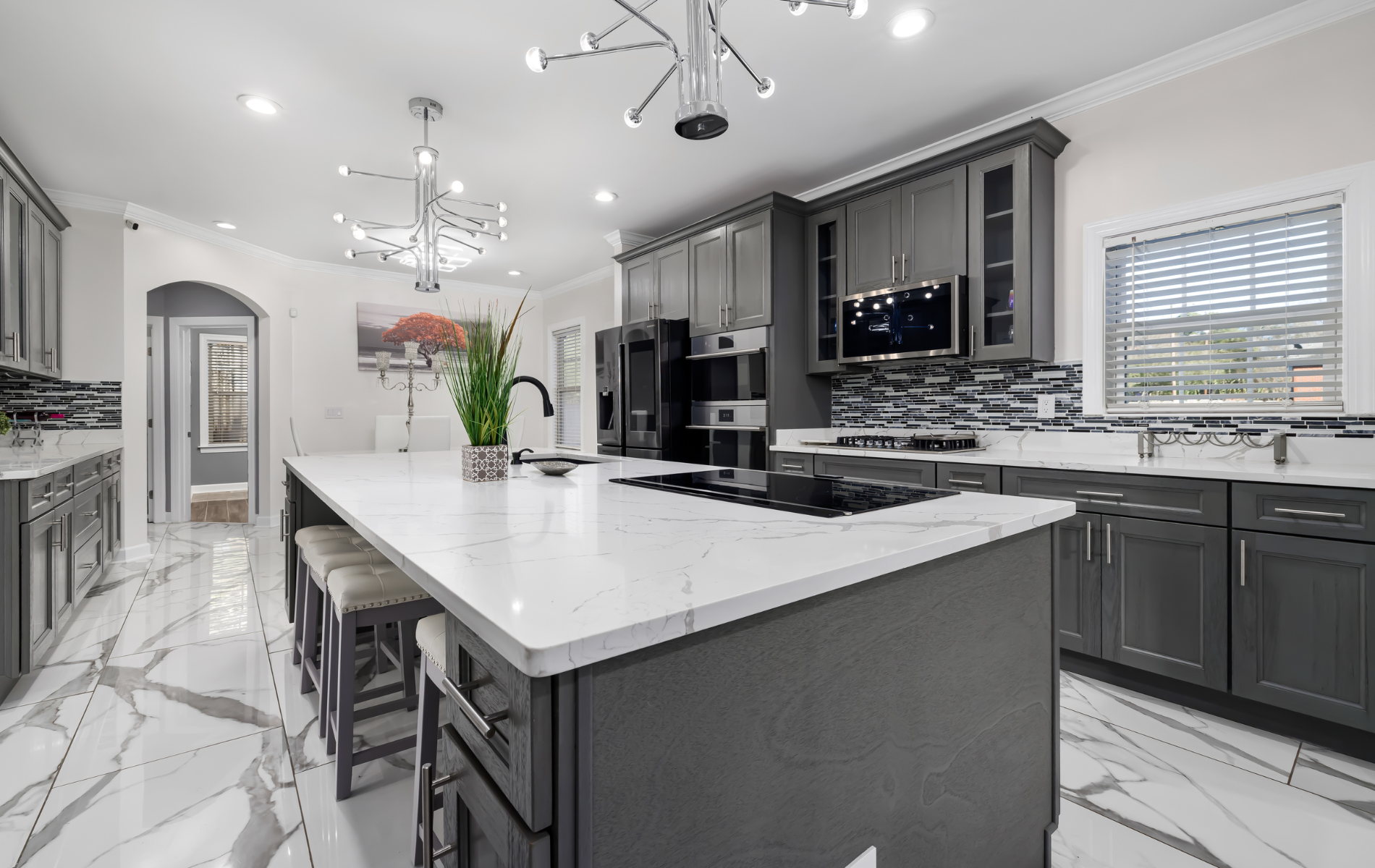Modern gray kitchen with large white island, marble floors, and stainless steel appliances