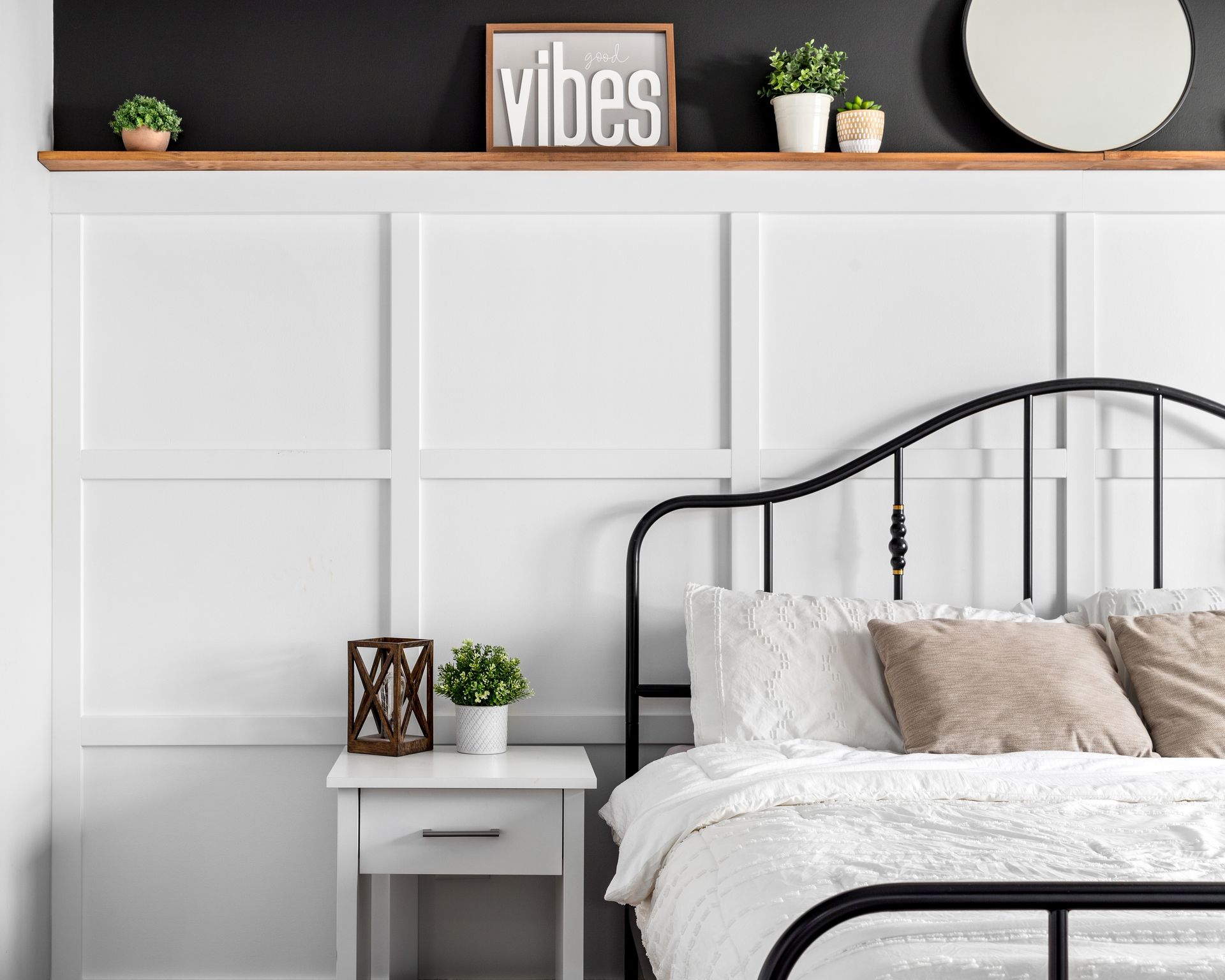 A bedroom with a bed , nightstand , mirror and shelf.