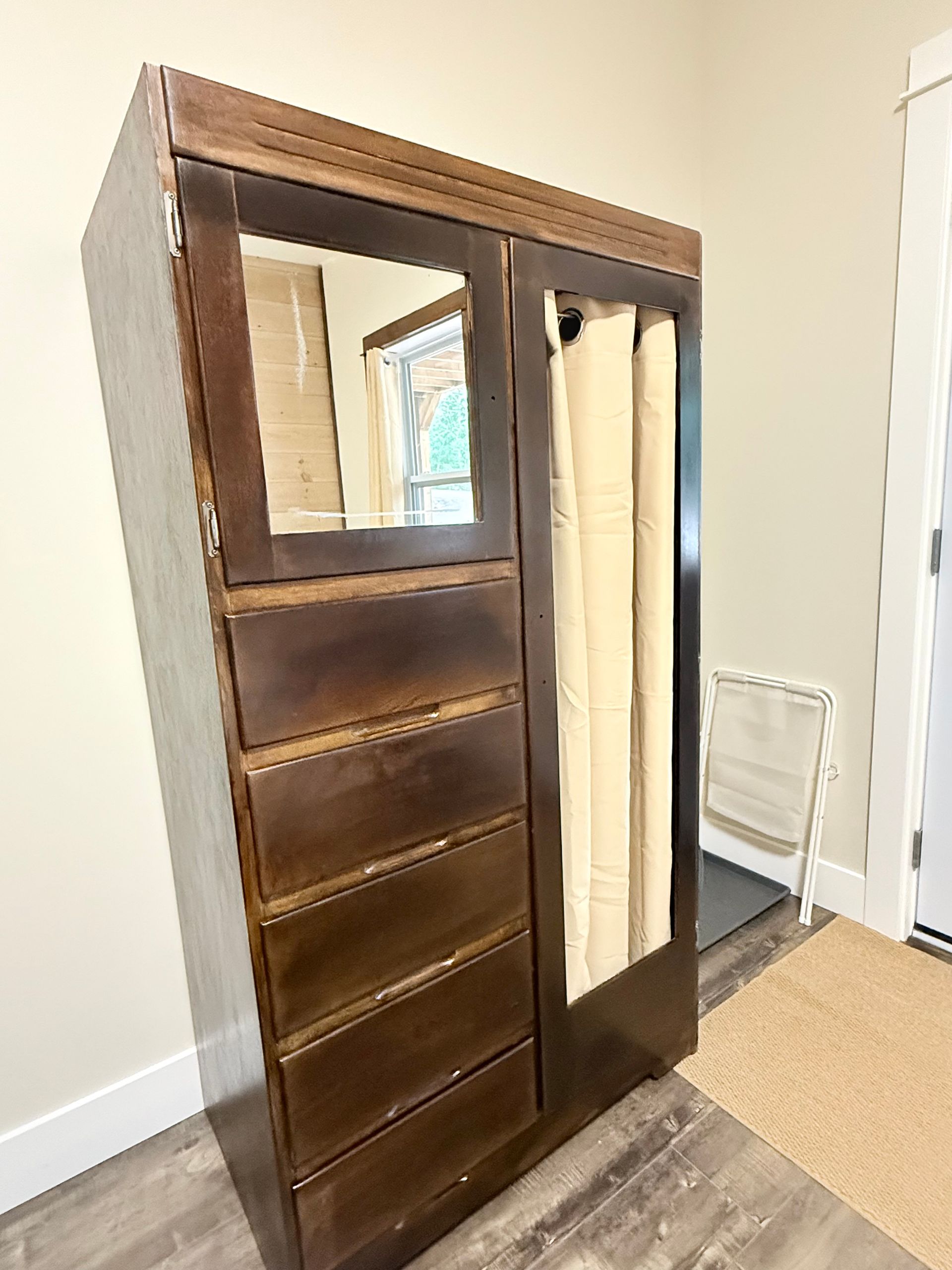 Wooden wardrobe with mirror door, shelves, and hanging section in a room corner