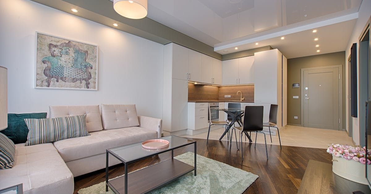 A living room with a couch, coffee table, chairs, and a kitchen.