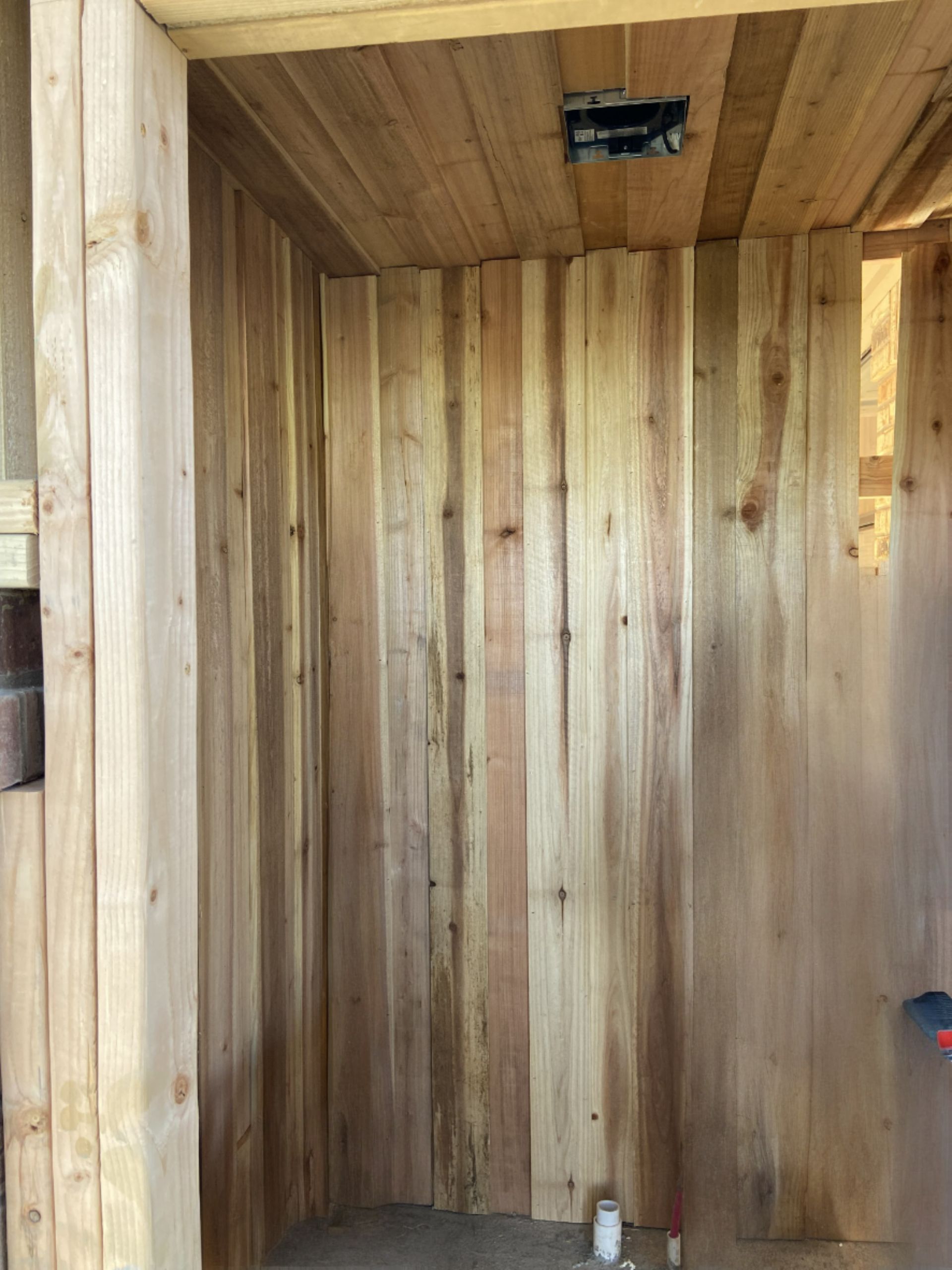 Wooden interior construction with cedar planks on walls and ceiling.