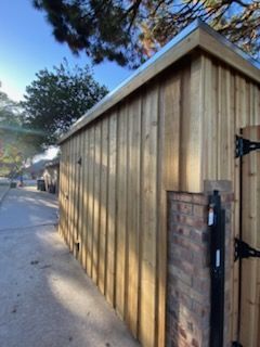 Wooden shed with brick and metal elements, next to a path under a blue sky.