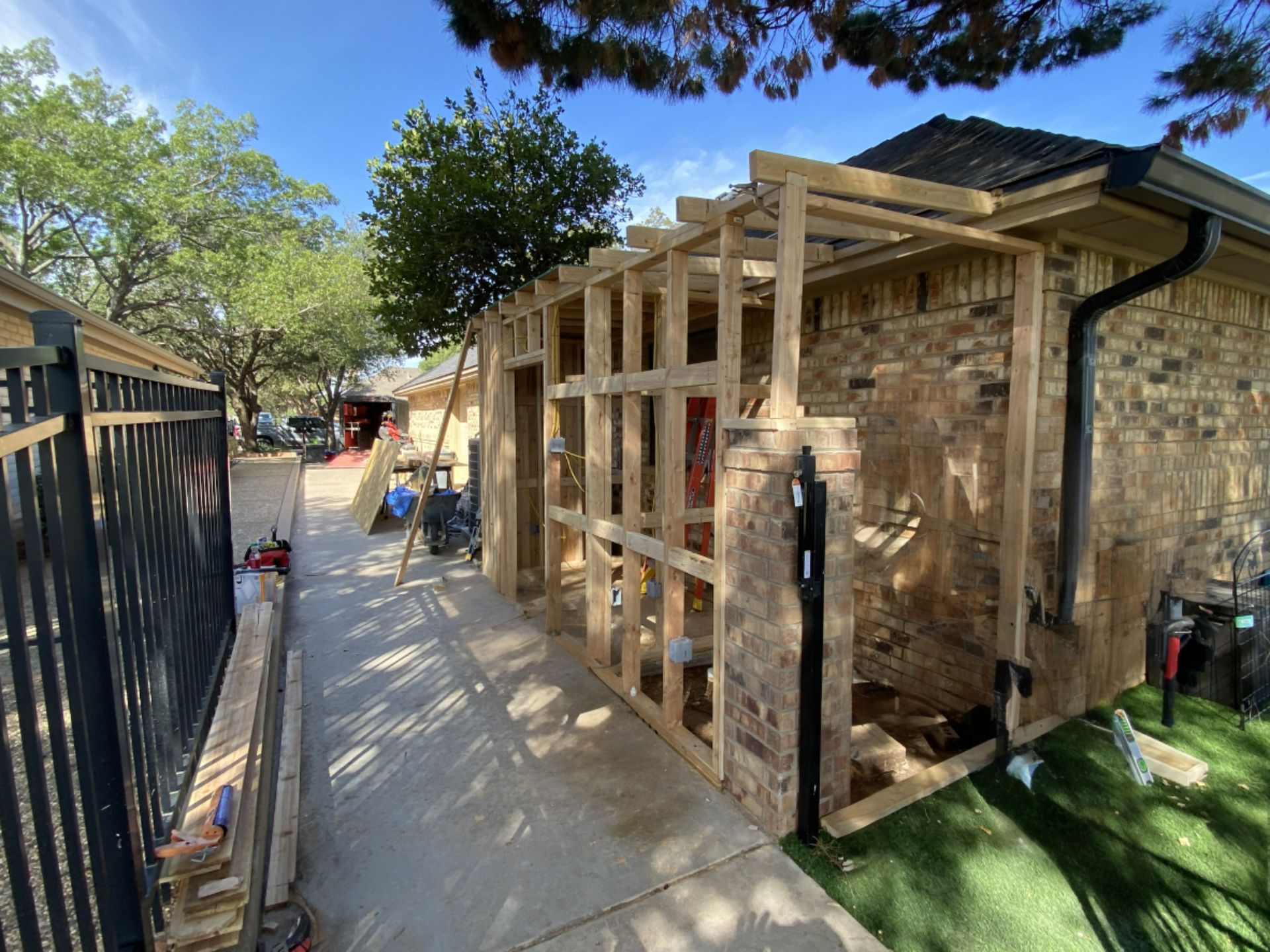 Wooden frame construction attached to a brick building; outdoor, bright daylight.