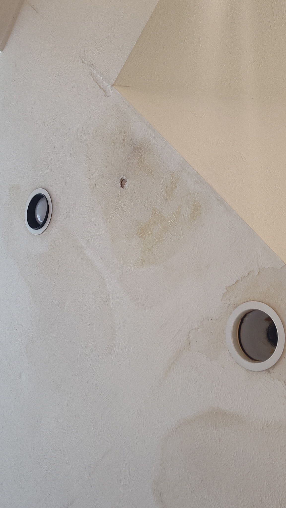 White ceiling with dark stains, two recessed lights.