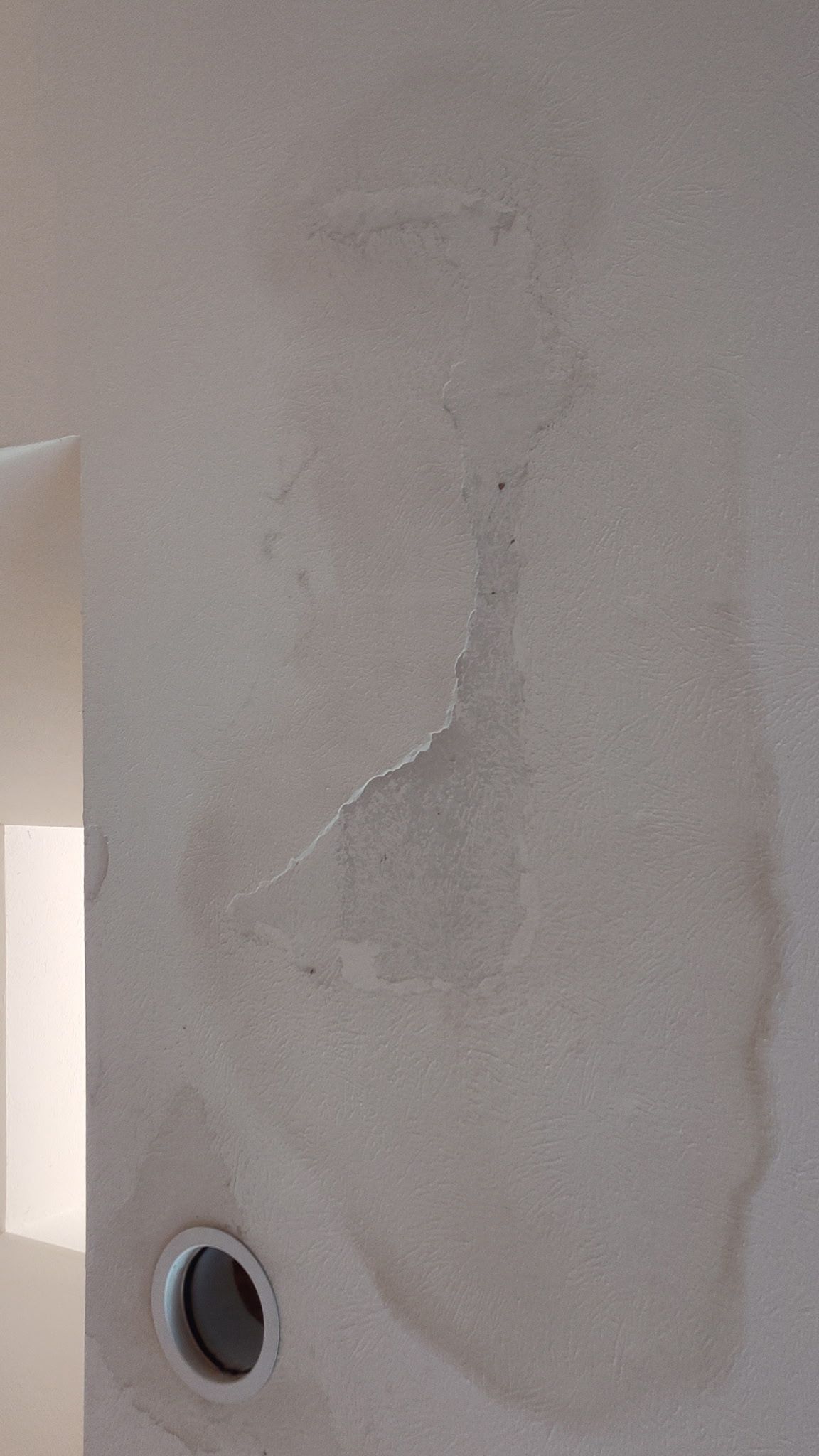Water stains on a beige wall, with a circular opening at the bottom left.