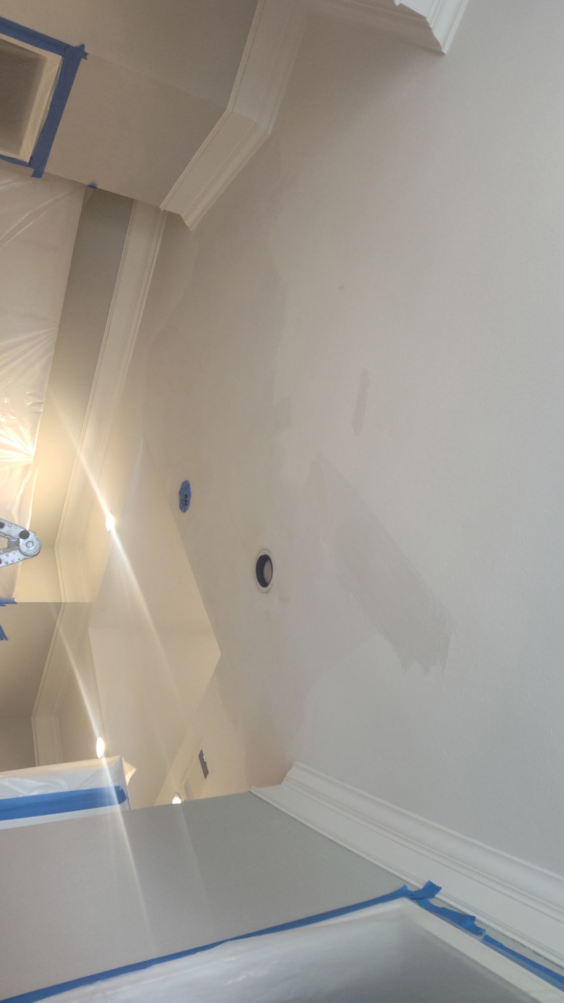 Interior wall partially painted, with blue painter's tape and a light fixture visible.