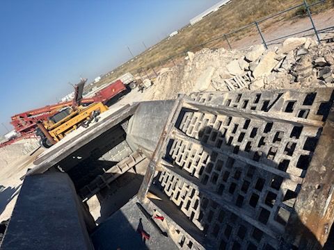 Construction site with a concrete processing machine, debris, and machinery.