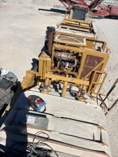 Yellow industrial machine on a concrete slab in an outdoor setting.