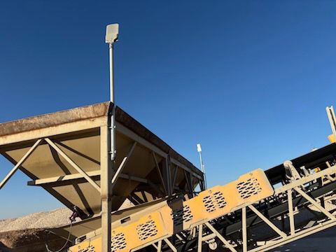 Industrial equipment with a conveyor belt and a metal structure, against a blue sky.