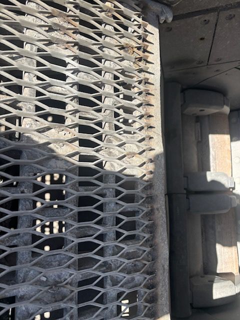 Metal grate surface next to a section of industrial equipment, possibly a walkway.