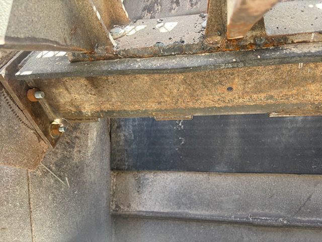 Close-up of a metal structure, showing bolts and beams. Rust and wear are visible.