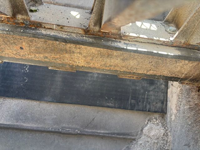 Black rubber sheet between metal beams. Some rust visible.