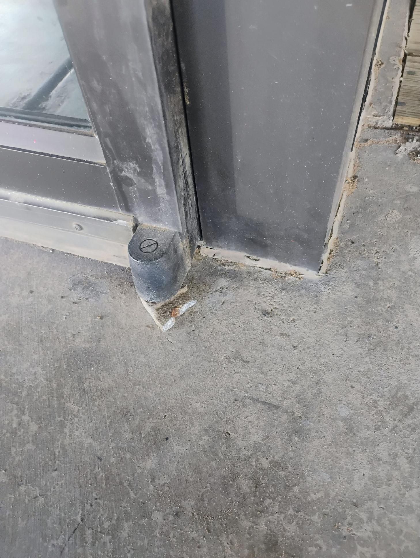 Door frame meets concrete floor, showing a rubber bumper at the bottom, likely for door stop.