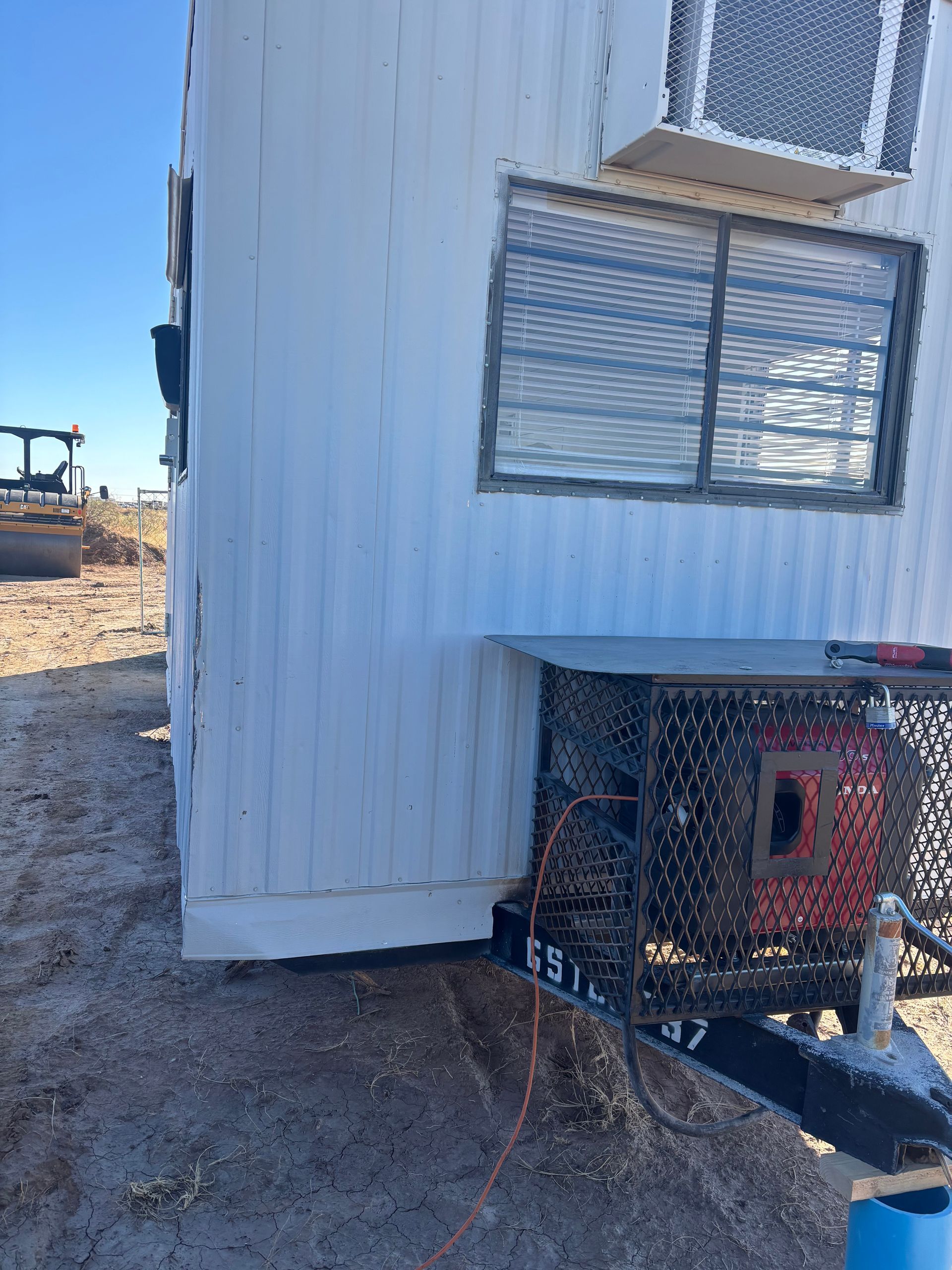 White storage container on trailer, black window with bars, metal cage with electrical components.