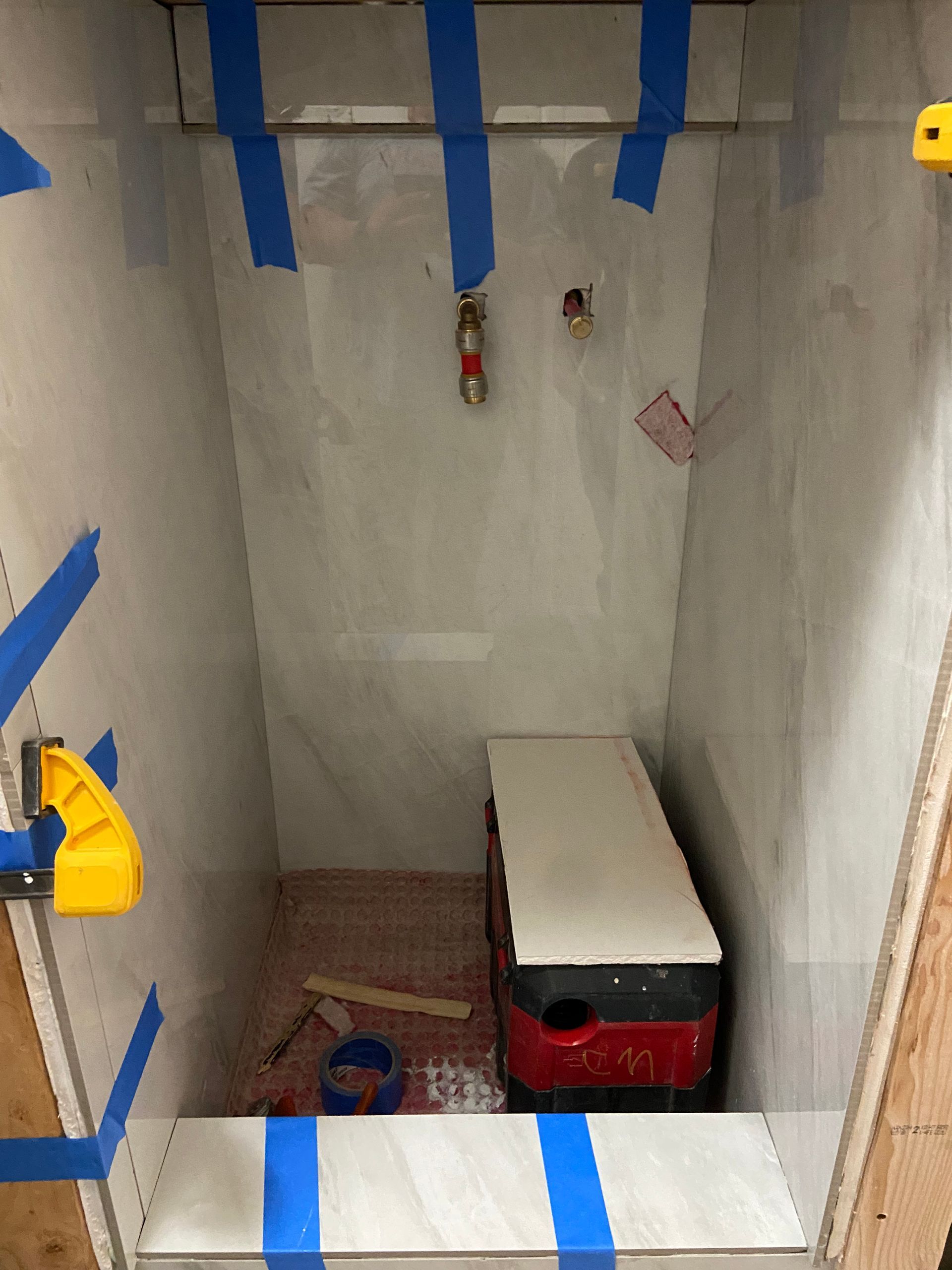 Small unfinished closet with plumbing fixtures, a small appliance, and blue tape.