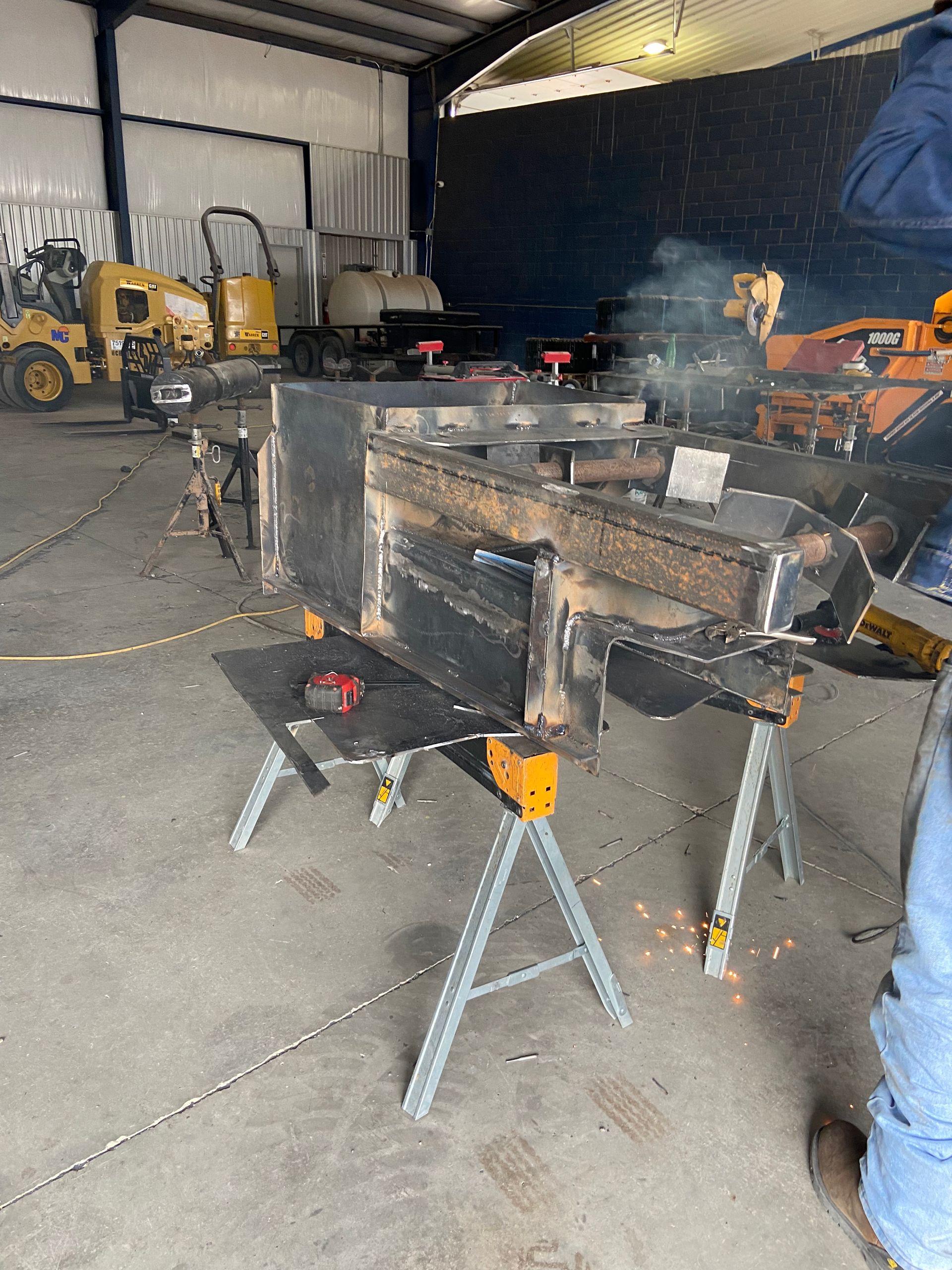 Welding in progress on large metal fabrication in a shop. Sparks fly.
