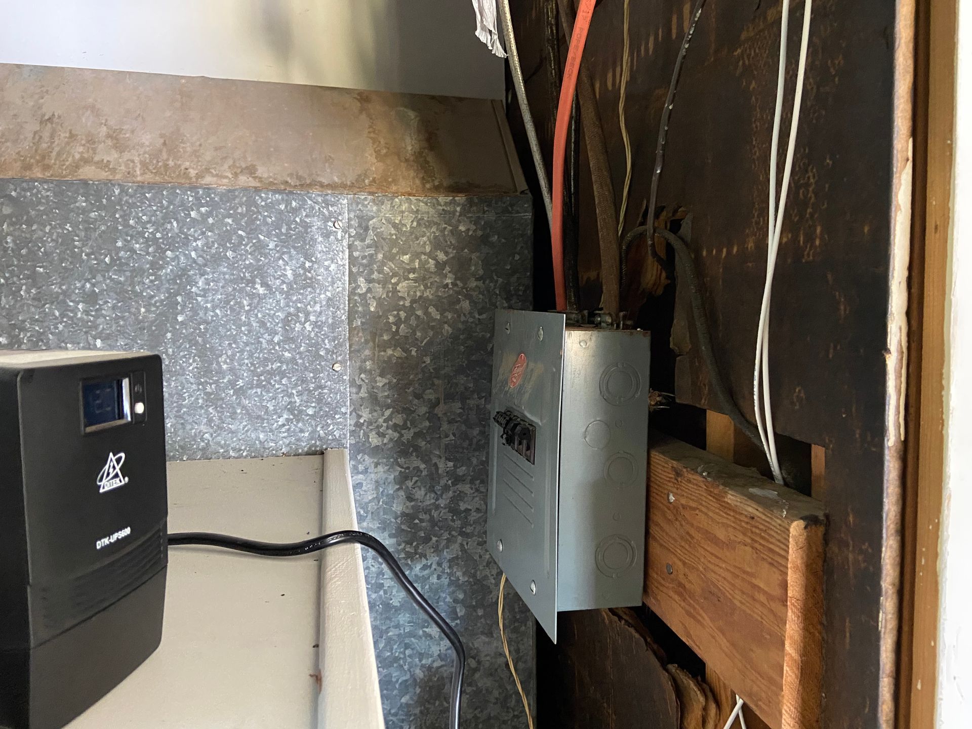 Electrical junction box and black UPS unit, with wiring in a basement setting.